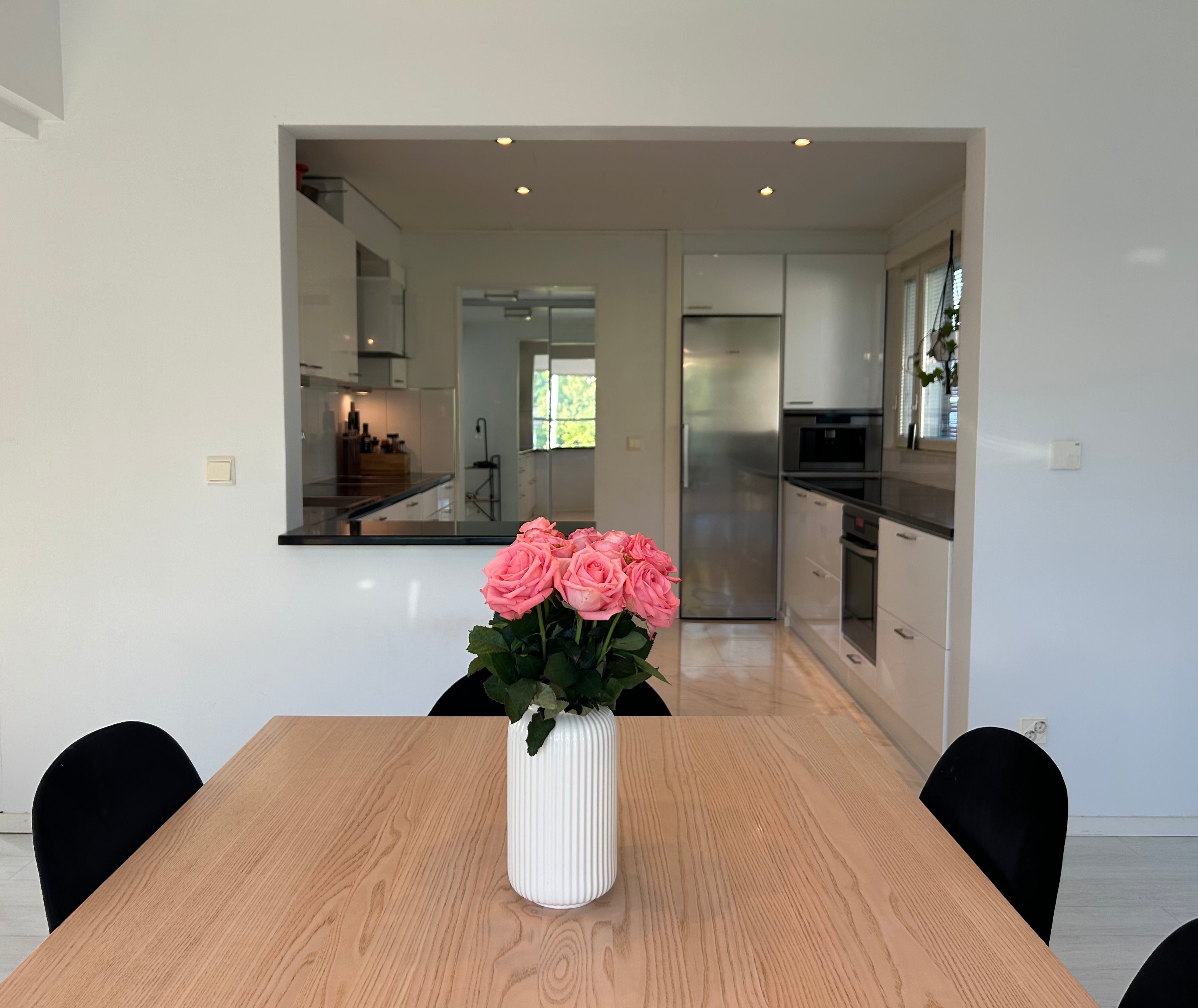 Modern kitchen with a dining table and vase of pink roses. Lapland Villa