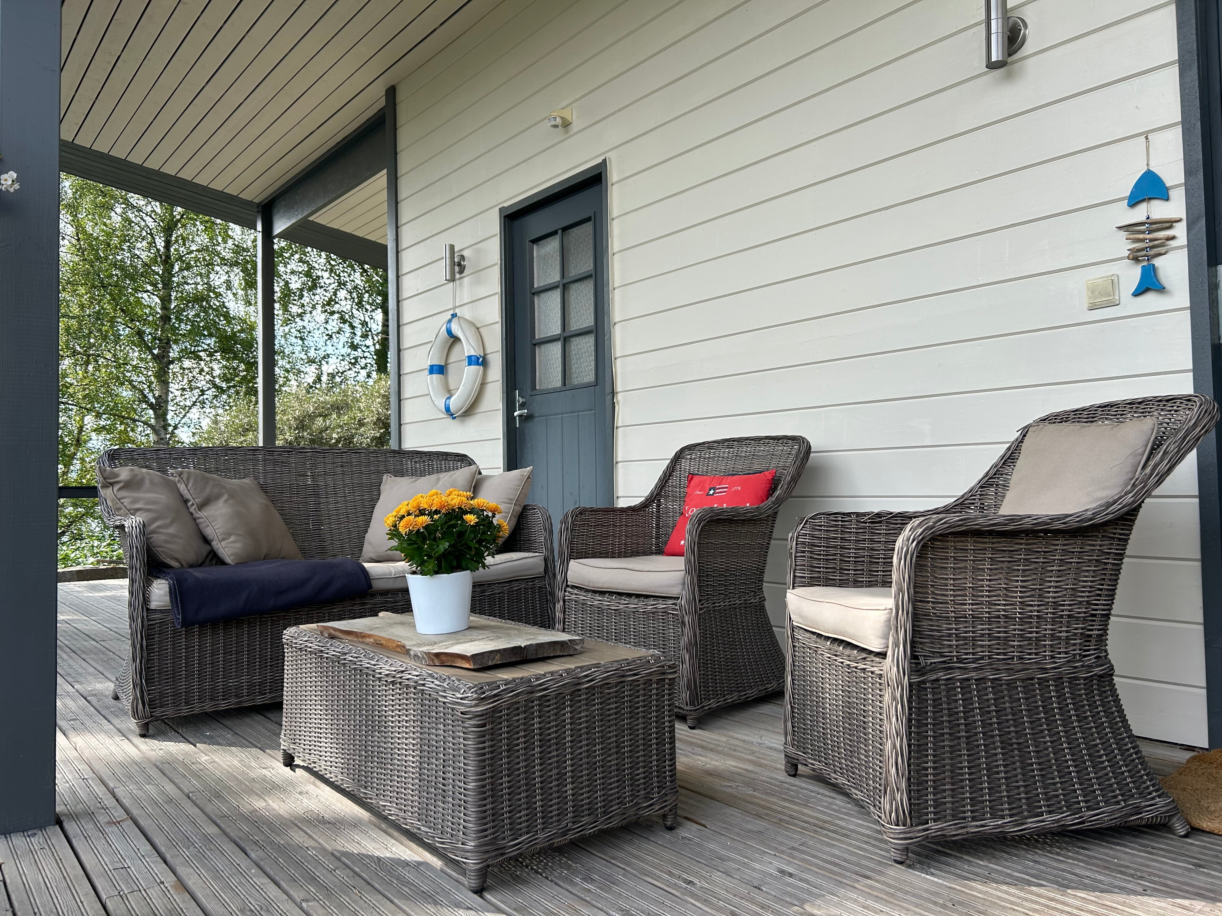 Outdoor patio furniture set on a wooden deck with a house in the background. Lapland Villa