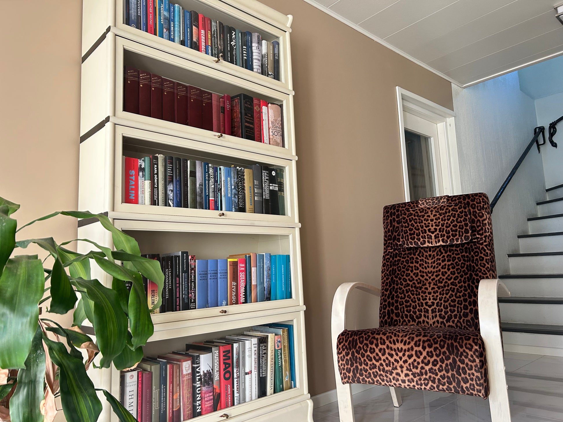 Bookshelf filled with books next to a chair with a leopard print pattern in a room.