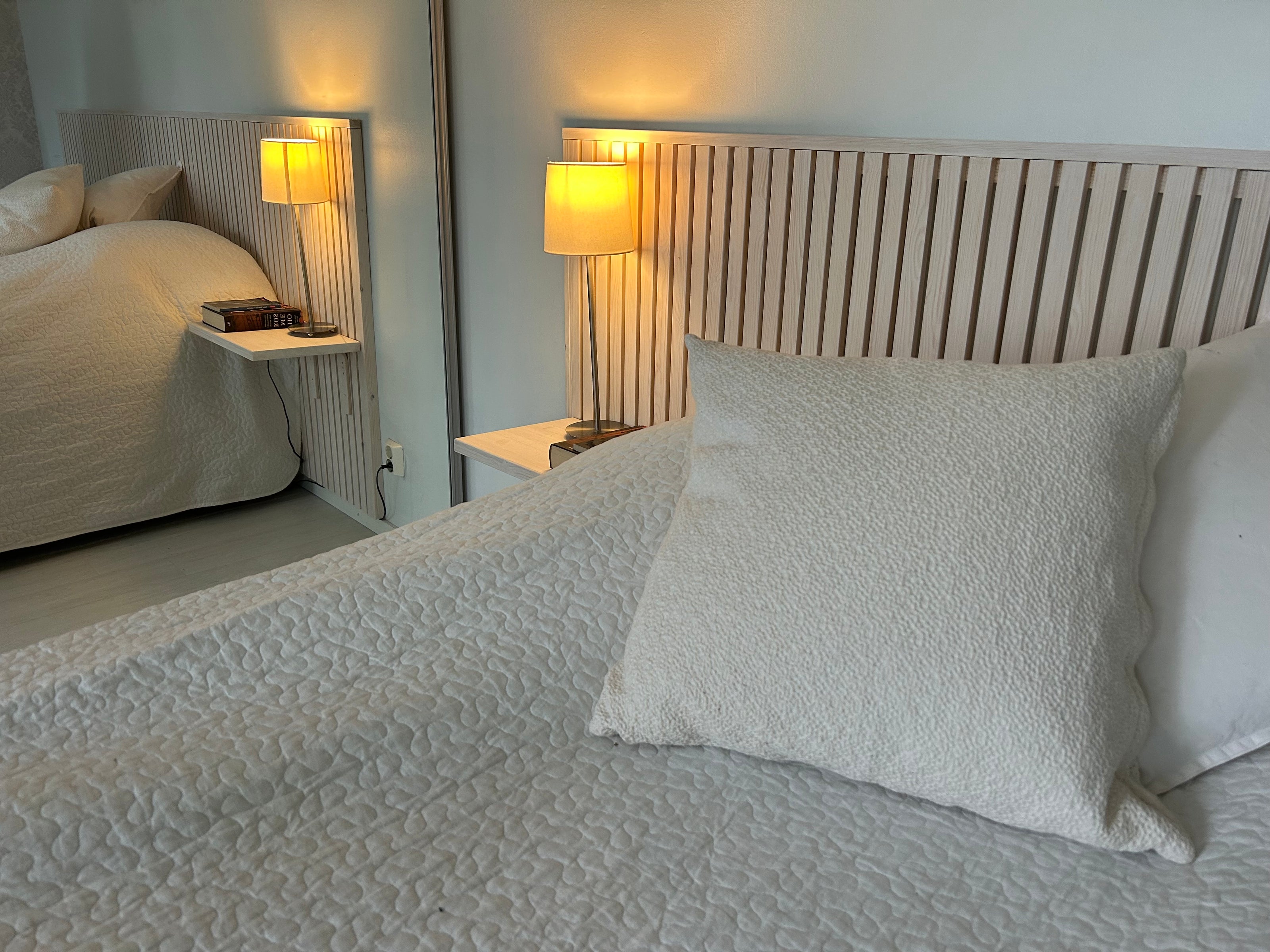 Bedroom with a bed featuring textured bedding and pillows, nightstands with lamps, in a Villa in Rovaniemi Lapland